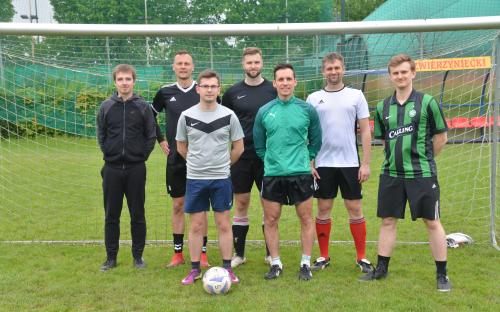 Zdjęcie nr 3: grupa siedmiu mężczyzn, stojących na boisku piłkarskim przed bramką do gry w piłkę nożną, przed nimi leży piłka do gry w piłkę nożną