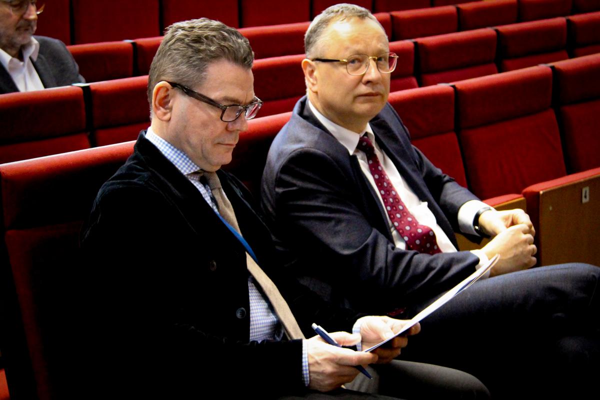 na zdjęciu widać 2 mężczyzn siedzących na sali wykładowej podczas konferencji